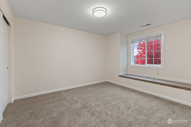 unfurnished room featuring a textured ceiling and carpet floors