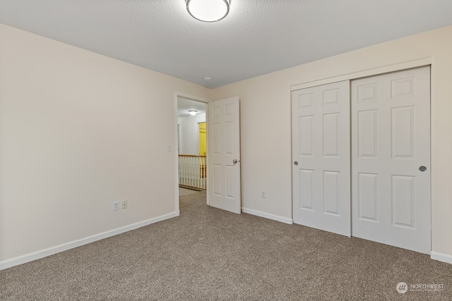 unfurnished bedroom featuring carpet, a textured ceiling, and a closet