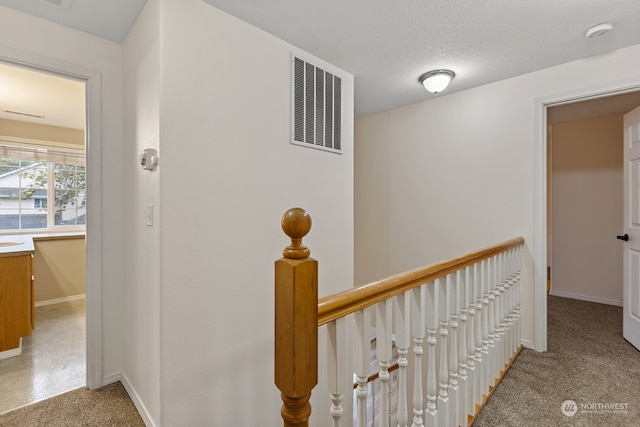 hallway with a textured ceiling and carpet