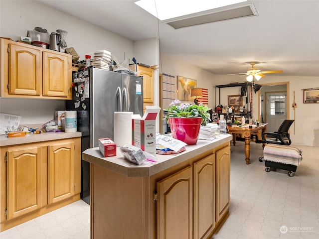 kitchen with ceiling fan, a skylight, light brown cabinets, and a kitchen island