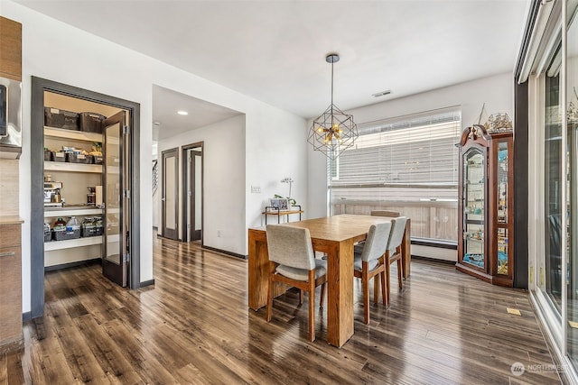 dining space featuring dark hardwood / wood-style flooring and an inviting chandelier