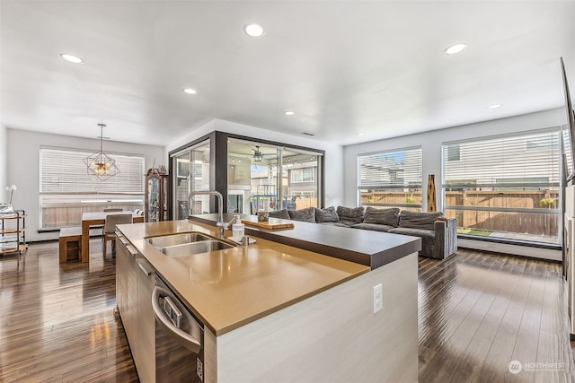 kitchen with a kitchen island with sink, dark wood-type flooring, hanging light fixtures, sink, and stainless steel dishwasher