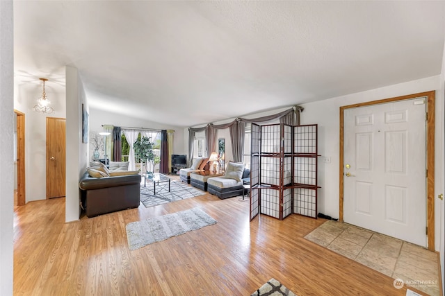 living room featuring light hardwood / wood-style floors, a notable chandelier, and lofted ceiling