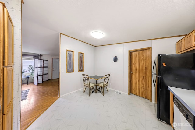 kitchen with a textured ceiling, white dishwasher, black fridge, crown molding, and light hardwood / wood-style flooring