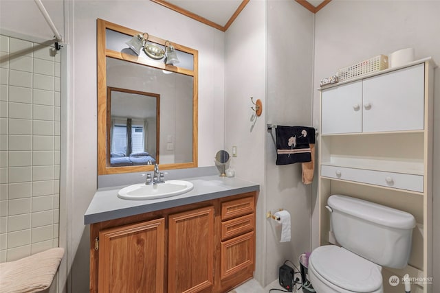 bathroom featuring toilet, ornamental molding, vanity, and a tile shower