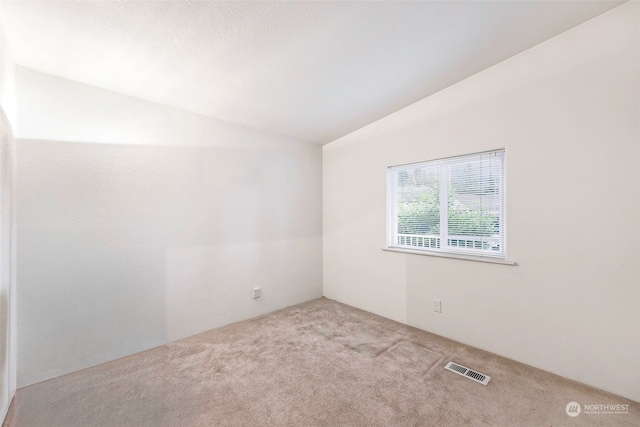 unfurnished room with vaulted ceiling and light carpet