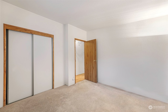 unfurnished bedroom with light colored carpet and a closet