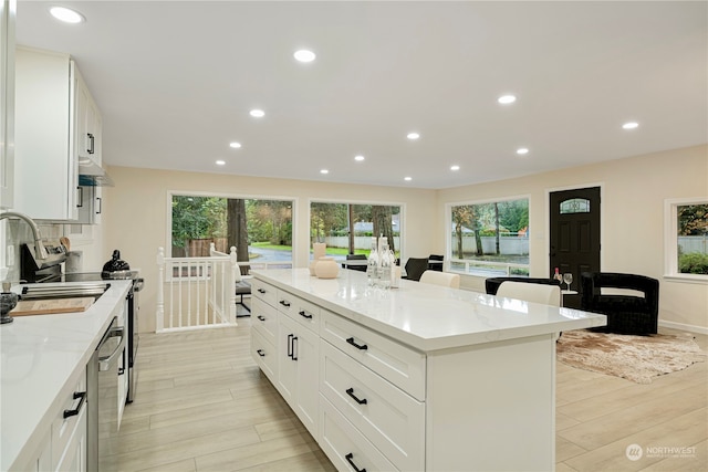 23405 NE 73rd St, Redmond, WA 98053 - kitchen featuring a healthy amount of sunlight, a center island, light hardwood / wood-style flooring, and white cabinetry