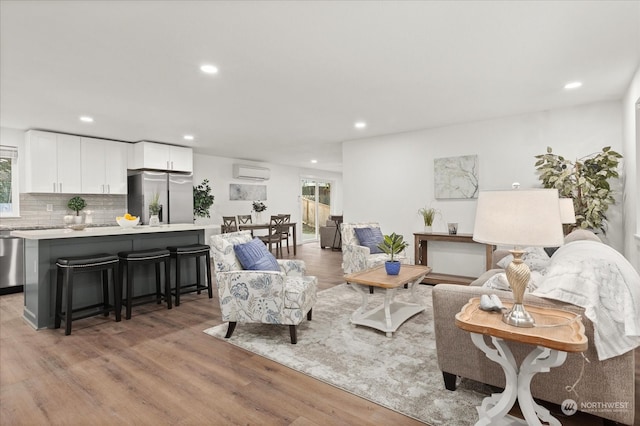 living room featuring light wood-type flooring and a wall mounted AC