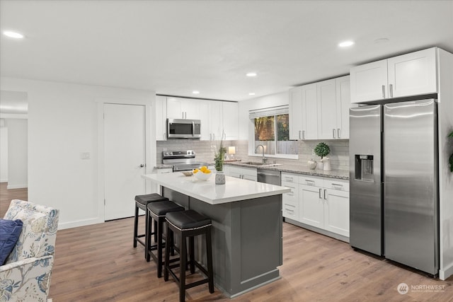 kitchen featuring white cabinets, hardwood / wood-style floors, sink, a kitchen island, and appliances with stainless steel finishes