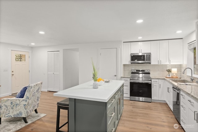 kitchen featuring white cabinetry, appliances with stainless steel finishes, sink, and light wood-type flooring