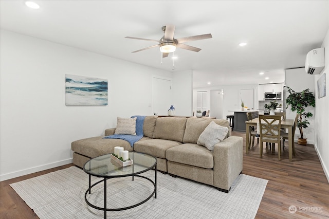 living room with a wall mounted AC, dark wood-type flooring, and ceiling fan