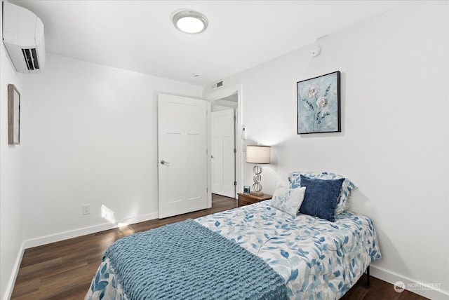 bedroom with dark wood-type flooring and a wall unit AC