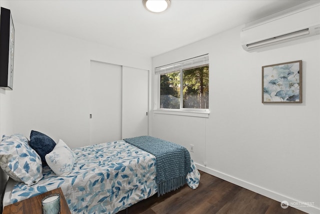 bedroom featuring a wall unit AC, a closet, and dark hardwood / wood-style flooring