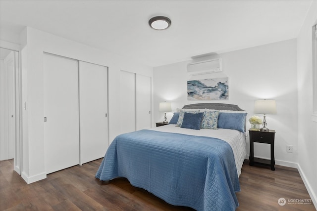 bedroom featuring dark hardwood / wood-style floors, multiple closets, and a wall mounted AC