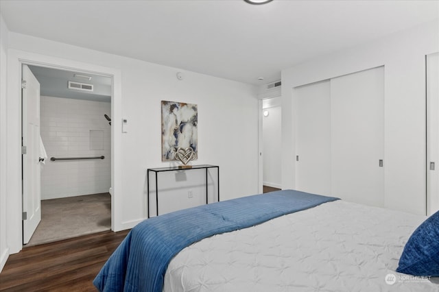 bedroom with dark wood-type flooring and connected bathroom