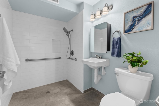 bathroom featuring toilet and a tile shower