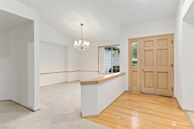 foyer entrance featuring light wood-type flooring, lofted ceiling, and an inviting chandelier