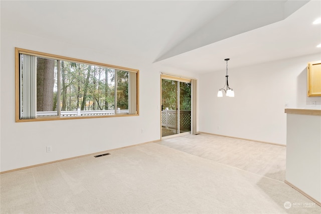 unfurnished living room with light carpet, vaulted ceiling, and a notable chandelier