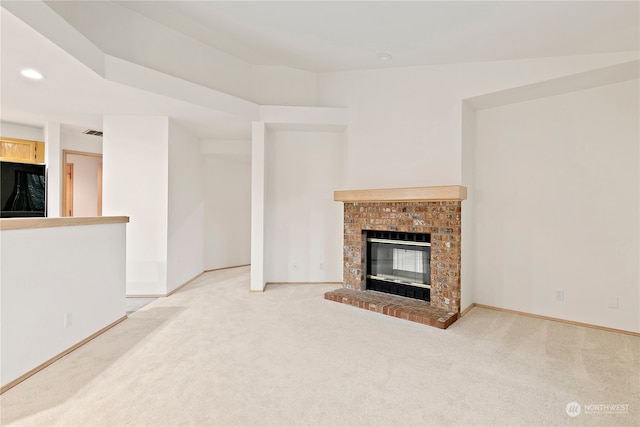 unfurnished living room featuring a brick fireplace and carpet flooring