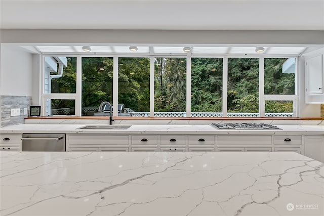 kitchen with sink, stainless steel appliances, white cabinetry, and decorative backsplash