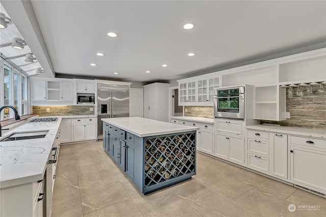 kitchen featuring built in appliances, a kitchen island, light stone countertops, and sink