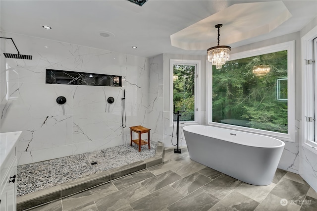 bathroom with separate shower and tub, a chandelier, and a raised ceiling