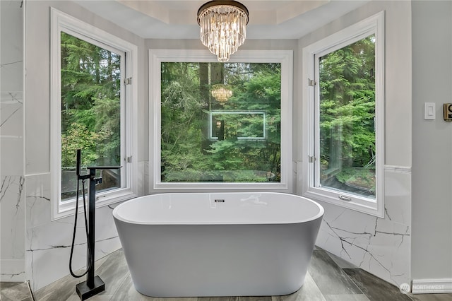 bathroom featuring a bath, a chandelier, and plenty of natural light