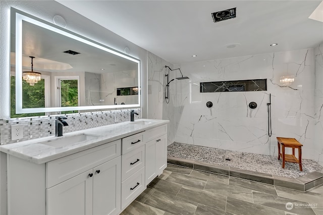 bathroom with vanity, an inviting chandelier, and a tile shower