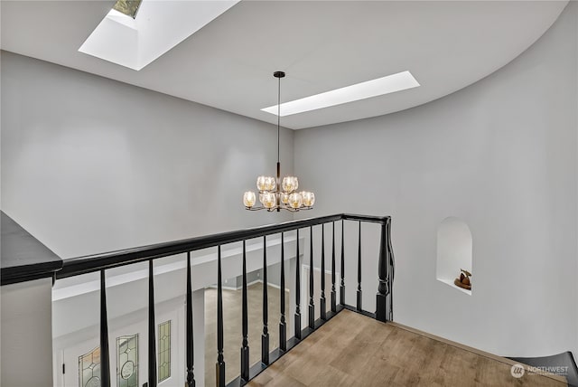 stairway featuring wood-type flooring, a chandelier, and a skylight