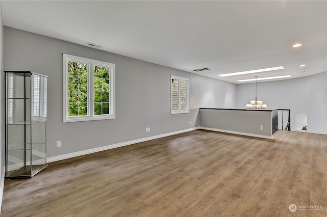 unfurnished room with a notable chandelier and light wood-type flooring