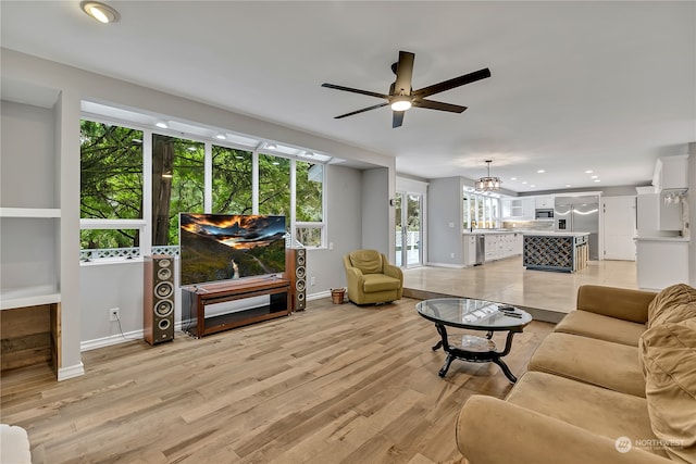 living room with light wood-type flooring and ceiling fan with notable chandelier