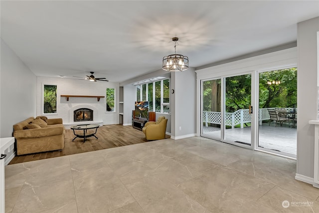 living room featuring ceiling fan with notable chandelier and a brick fireplace