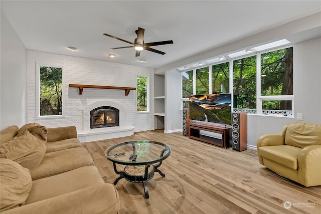 living room featuring a fireplace, a healthy amount of sunlight, light hardwood / wood-style flooring, and ceiling fan