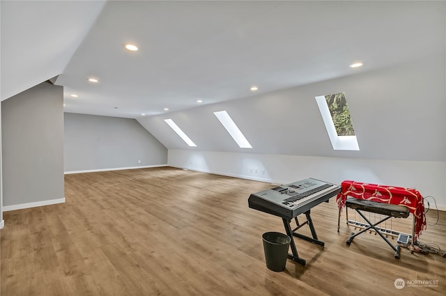 bonus room with wood-type flooring and lofted ceiling with skylight