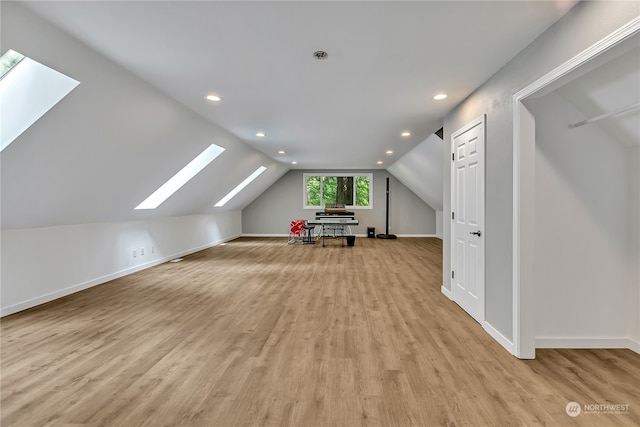 additional living space featuring lofted ceiling with skylight and light hardwood / wood-style floors