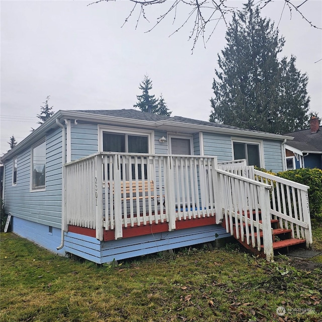 rear view of house featuring a yard and a wooden deck