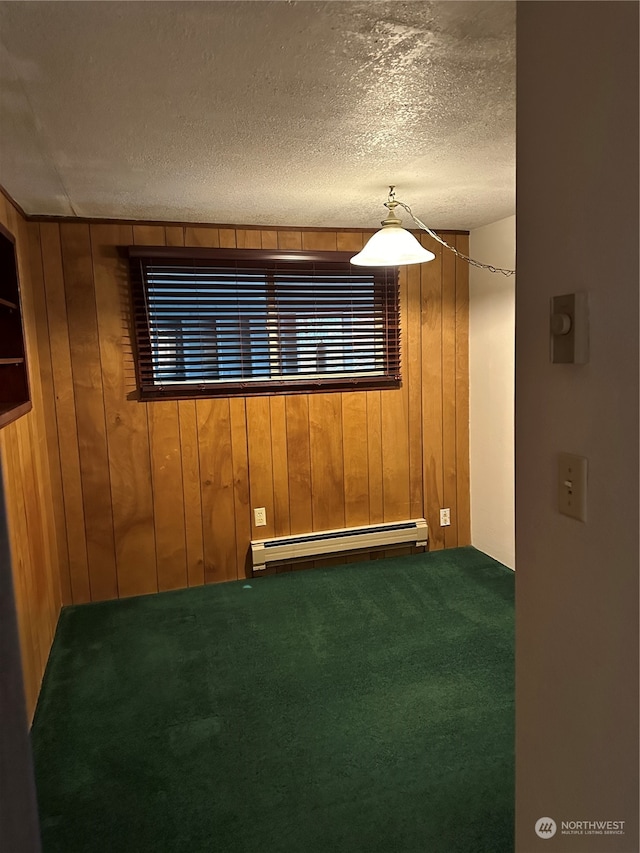 carpeted spare room featuring baseboard heating, a textured ceiling, and wood walls