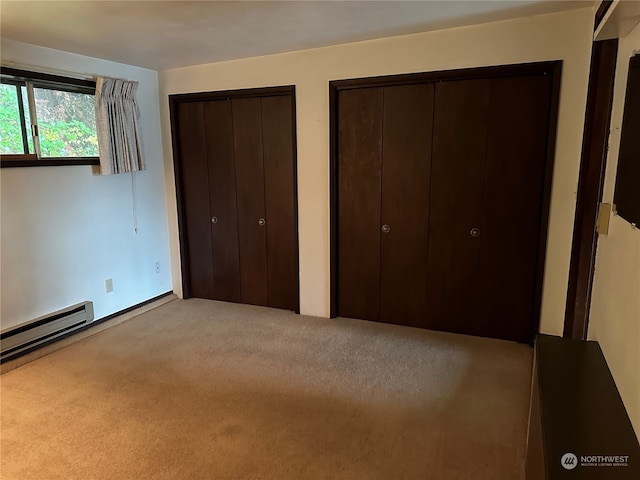 unfurnished bedroom with light carpet, a baseboard radiator, and two closets