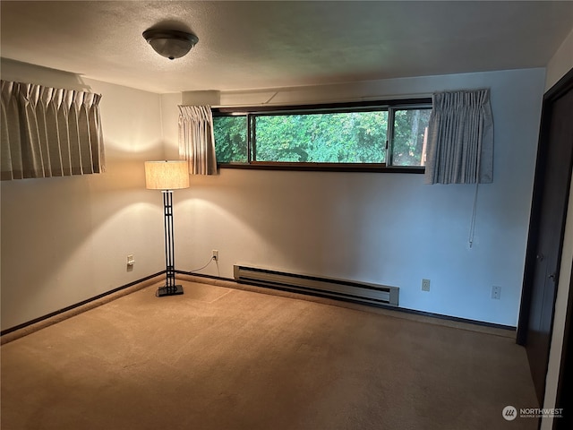 carpeted spare room with a baseboard heating unit