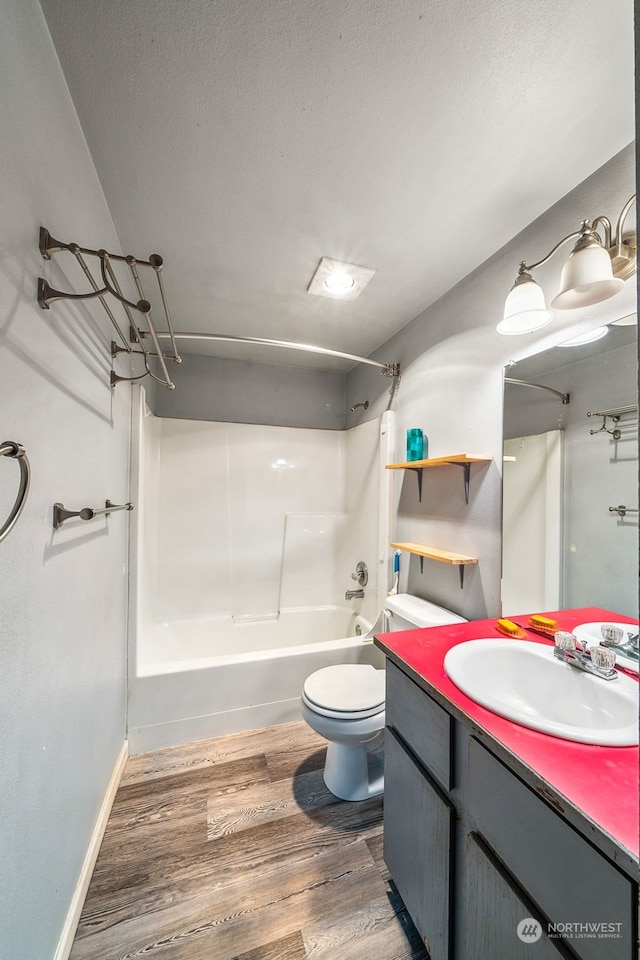 full bathroom with toilet, hardwood / wood-style floors,  shower combination, vanity, and a textured ceiling