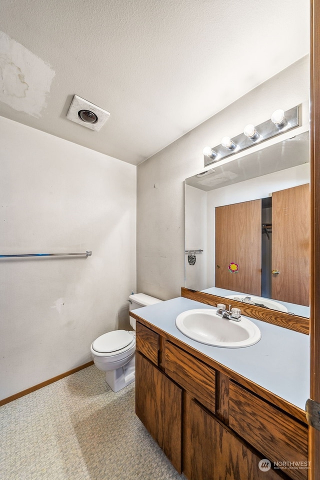 bathroom featuring vanity, toilet, and a textured ceiling