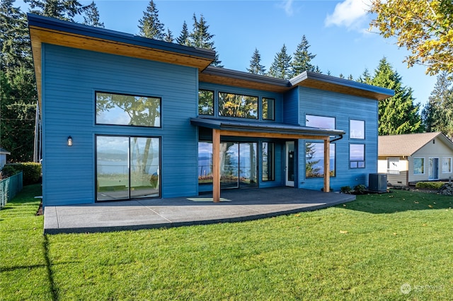 rear view of property with a yard, cooling unit, and a patio