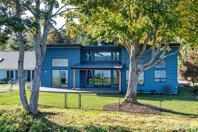 rear view of house with central air condition unit and a lawn