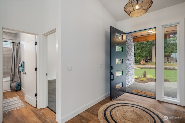 entryway with vaulted ceiling, wood finished floors, and baseboards