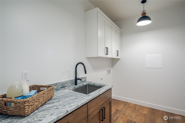 clothes washing area with sink, hookup for a washing machine, light hardwood / wood-style floors, and cabinets