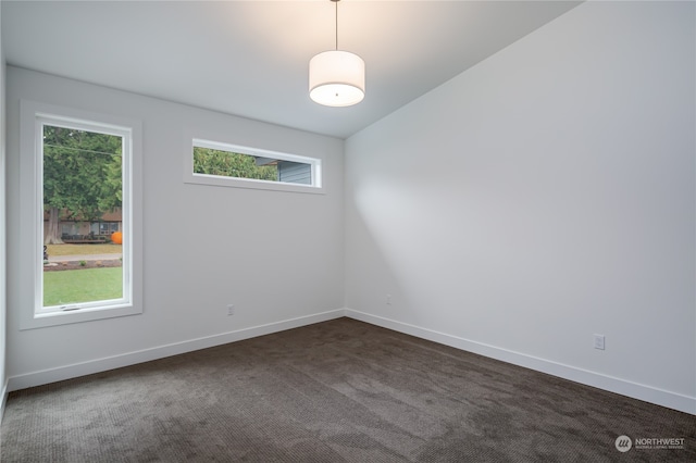 spare room featuring vaulted ceiling, plenty of natural light, and dark carpet