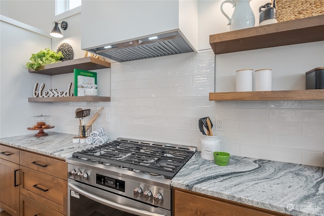 kitchen with backsplash, island exhaust hood, light stone counters, and high end stainless steel range oven