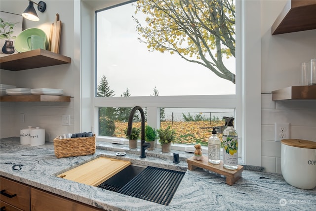 details featuring backsplash, light stone countertops, and sink