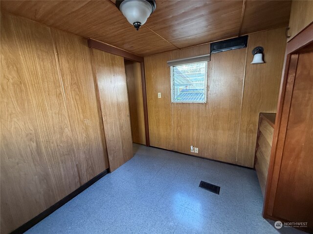 empty room with wood ceiling and wooden walls